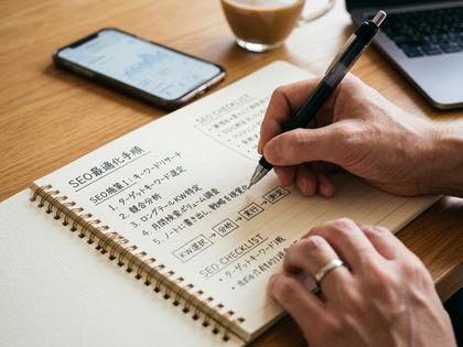 ノートにSEO対策の手順を書き出している手元のクローズアップ画像